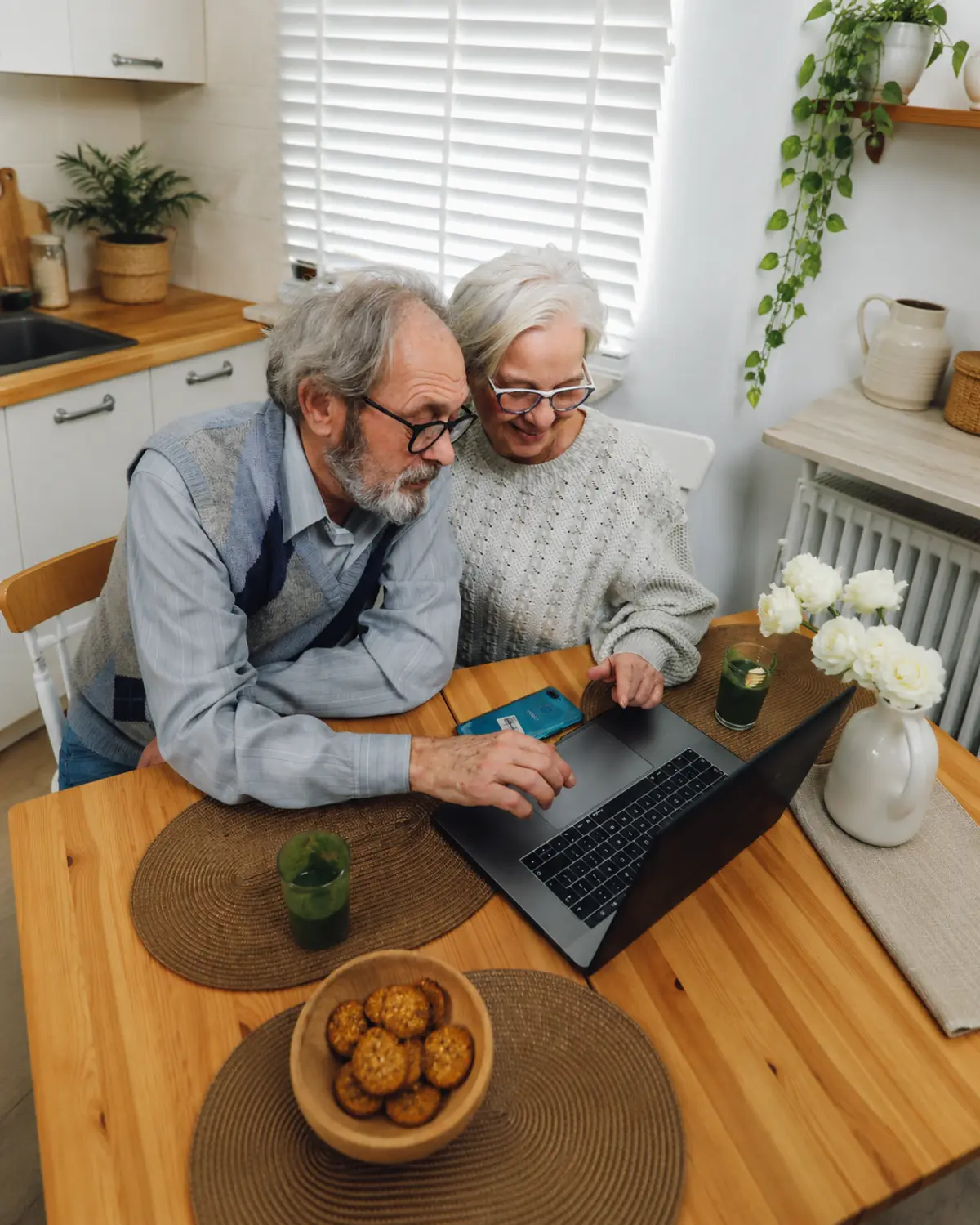 An older couple at their kitchen table, going through their LPA together on a laptop